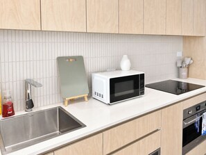Eine moderne Küche mit einer Edelstahl-Spüle, einer weißen Mikrowelle und einem Holzkasten.