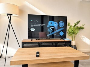 Ein Fernseher auf einem Holzständer, mit einer Fernbedienung auf einem Tisch davor.