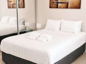 A hotel room with a large bed, two bedside tables, and a mirror. - Vibrant 1BR Stay in Braddon | Parking | Near Tram (Braddon)