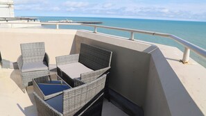 A balcony with wicker furniture and a view of the sea.
