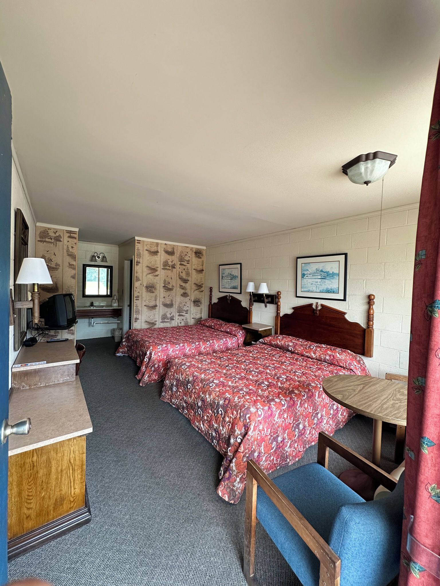 Une chambre d’hôtel avec deux lits, un bureau, une télévision et une fenêtre.