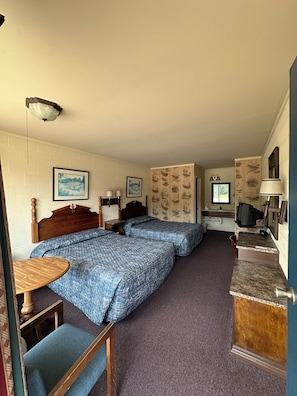 A room with two beds, a desk, a chair, a television, and a wall with framed pictures. - PARIS LANDING MOTEL (Buchanan)