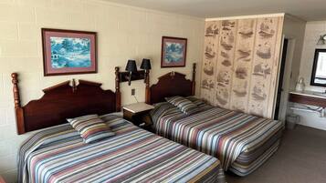Habitación de hotel con dos camas, una mesita de noche, una lámpara, un marco de fotos y un papel tapiz con motivos naturales.