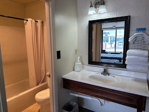 Ein Badezimmer mit einer Badewanne, Toilette, Waschbecken und einem Spiegel.
