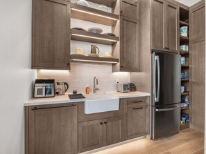 A modern kitchen with wooden cabinets, a stainless steel refrigerator, and a built-in oven. - Timpanogos View Estate at Red Ledges (Heber City)