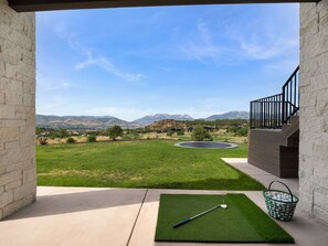 A patio with a golf mat, a golf club, and a basket of golf balls. - Timpanogos View Estate at Red Ledges (Heber City)