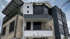 Um edifício moderno de dois andares com teto plano, varanda no andar superior e entrada no nível da rua.