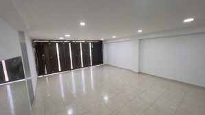 Um quarto amplo com piso de azulejos, porta com moldura preta e iluminação embutida no teto.