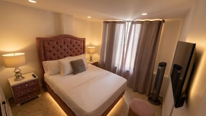 Ett hotellrum med en stor säng, sänglampor, en platt-TV och en fristående värmare.