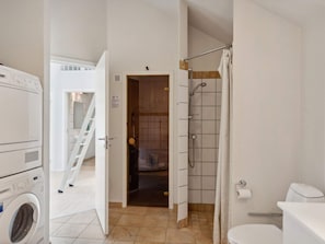 A bathroom with a toilet, shower, and a washing machine. - 8 Person Holiday Home in Egernsund (Broager)
