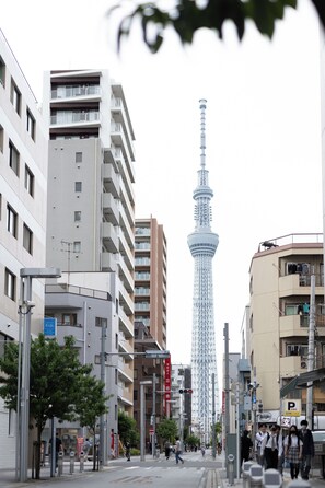 Una calle urbana con edificios modernos, una torre destacada y peatones.