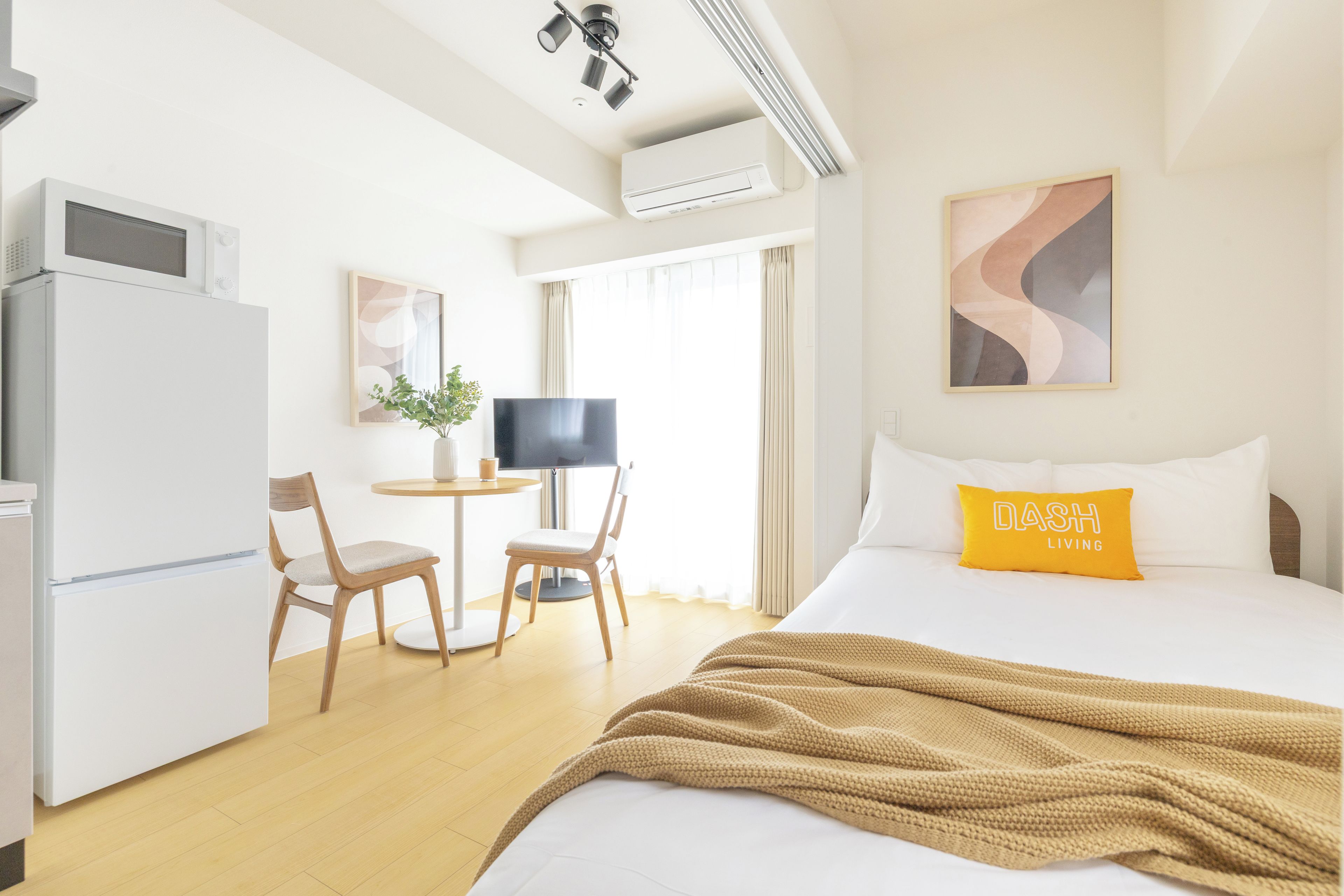 Habitació d'hotel amb un llit, un escriptori, una cadira, una televisió i un aire condicionat.
