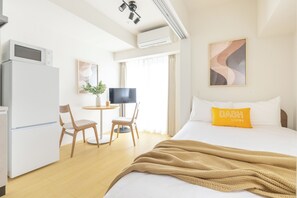 Habitación de hotel con cama, escritorio, silla, televisor y aire acondicionado.