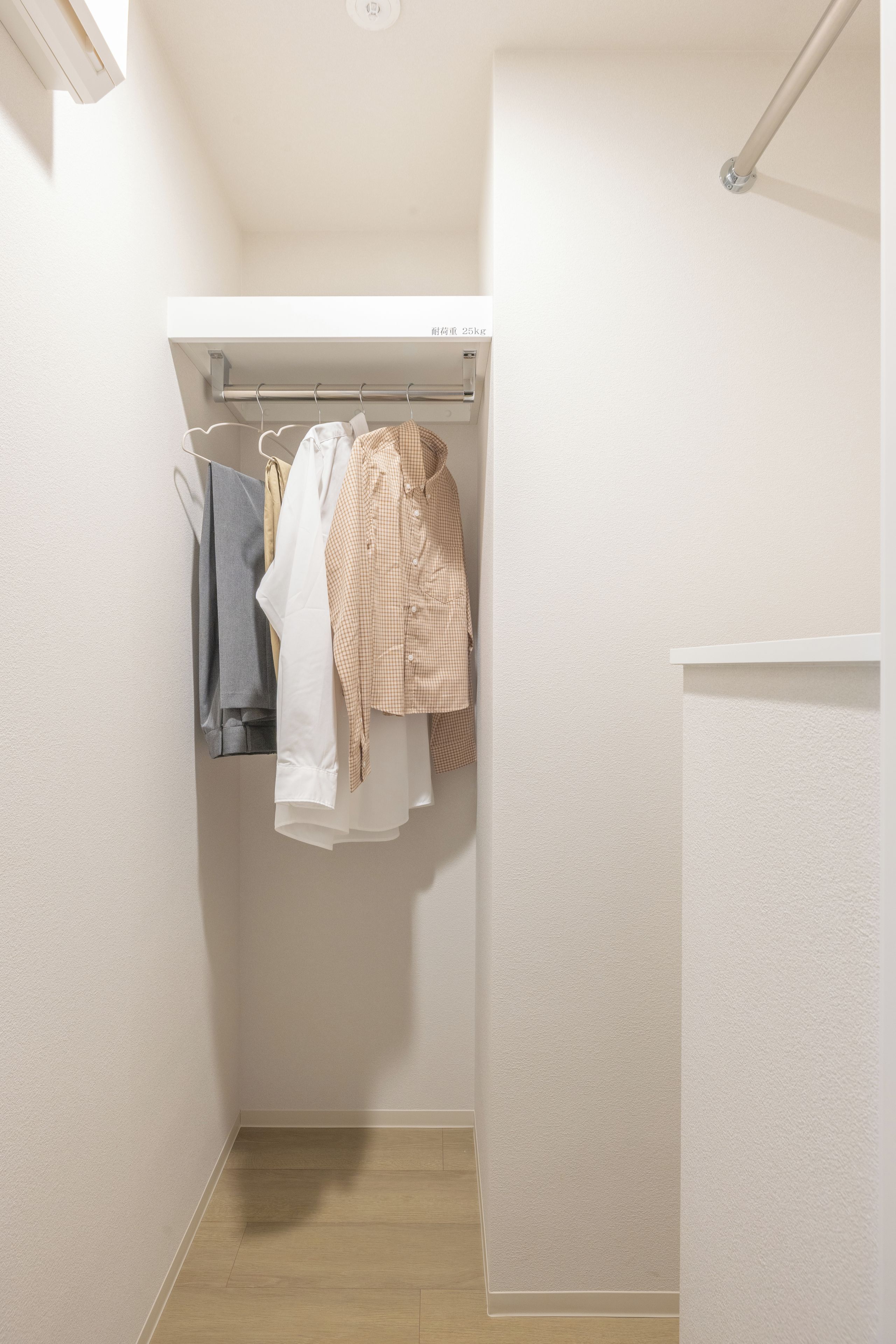 A small, narrow closet with a wooden floor and a white wall.