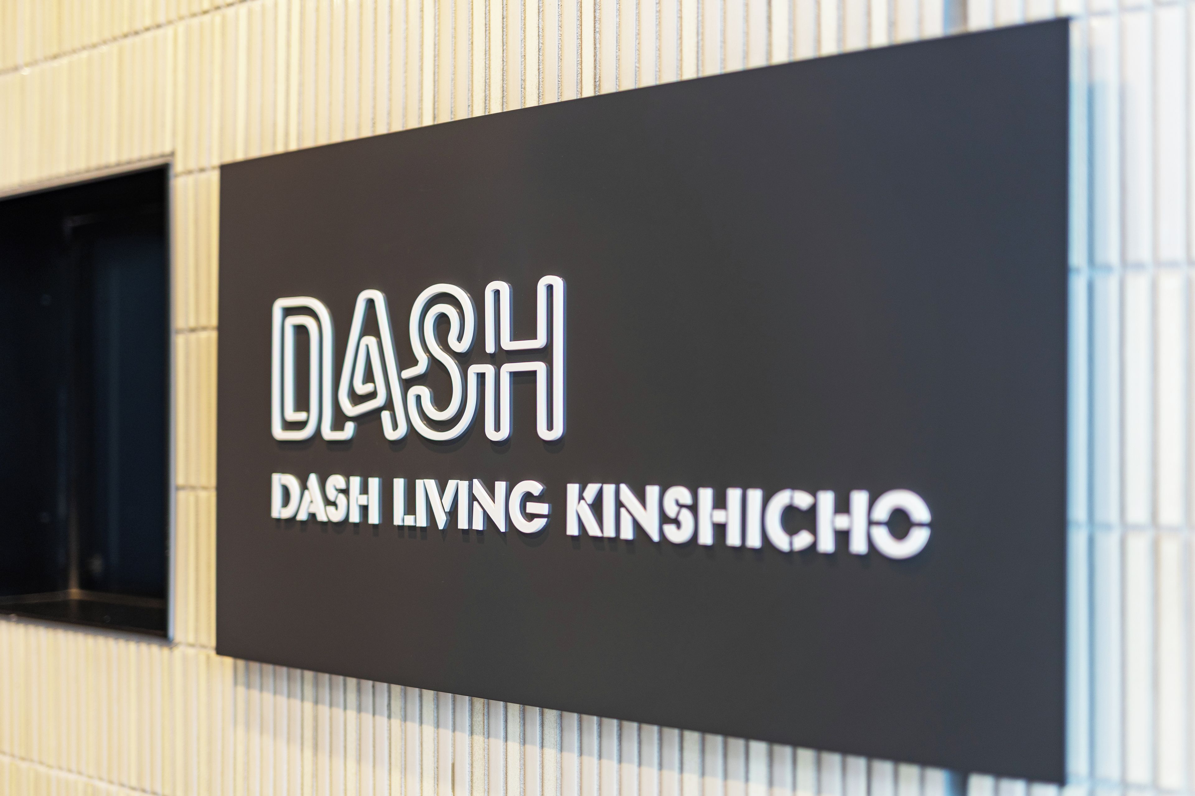 A sign with the text 'DASH DASH LIVING KINSHICHO' on a black background.