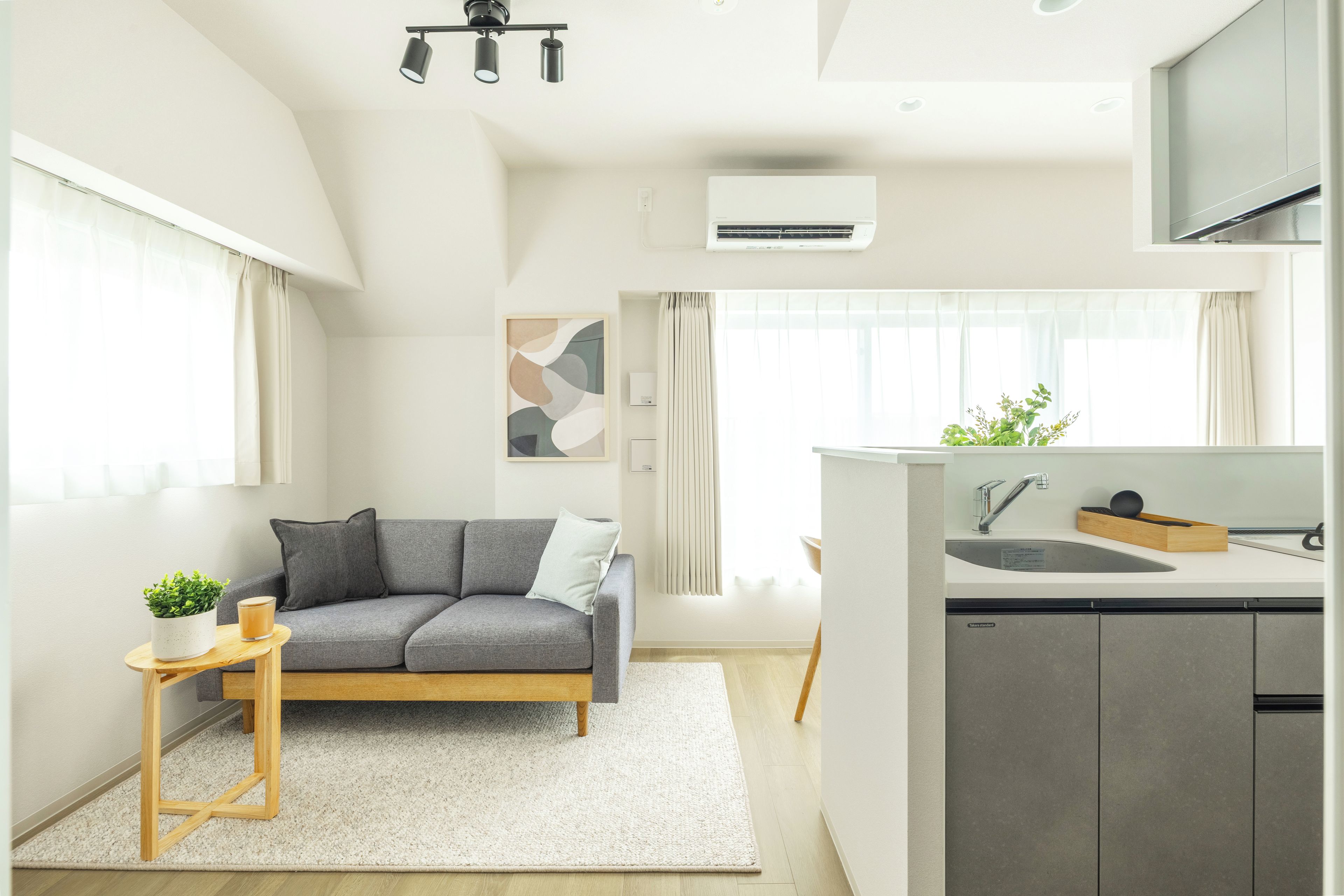 A modern living room with a grey sofa, a small wooden side table, and a white rug.