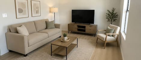 A modern living room with a sofa, coffee table, TV stand, and a ceiling fan.