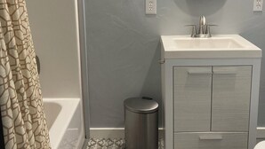 A bathroom with a white sink, a mirror, a trash bin, and a patterned floor. - 4 bed 3.5 bath on 5 acres 5 minutes to Walmart supercenter and 6 minutes to OSU. (Stillwater)