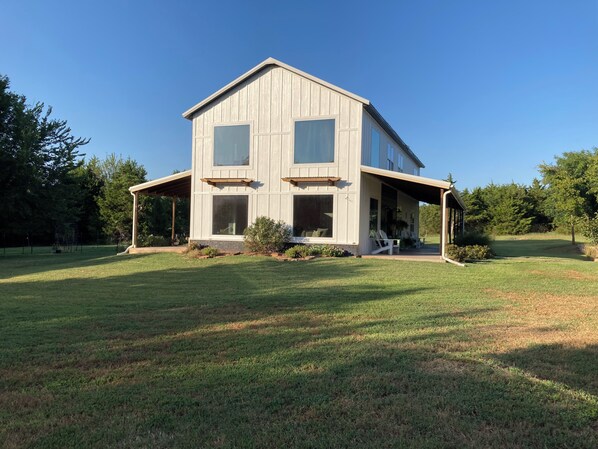 Uma casa de dois andares com varanda coberta e gramado frontal.
