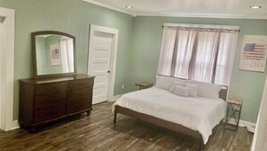 A bedroom with a wooden bed, a dresser, a mirror, a door, and a window with curtains. - 4 bed 3.5 bath on 5 acres 5 minutes to Walmart supercenter and 6 minutes to OSU. (Stillwater)