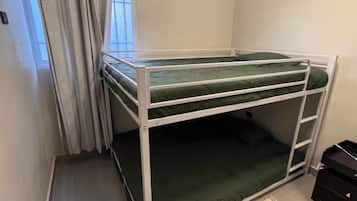 A bunk bed in a room with a window, curtains, and a rug.