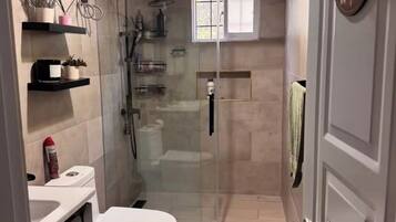 Une salle de bain moderne équipée de toilettes, d’une douche et d’un espace de douche vitré.