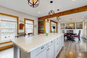 A spacious kitchen with a large island, wooden beams, and modern lighting fixtures. - Family-Friendly Vermont Retreat Near Mount Snow | VAST Trail Access & Walk to Downtown (Wilmington)