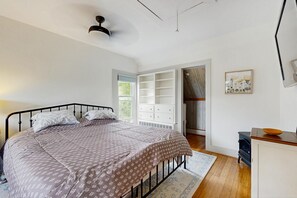 Ein Schlafzimmer mit einem Bett, einem Schminktisch, einem Heizkörper und einem Fenster.