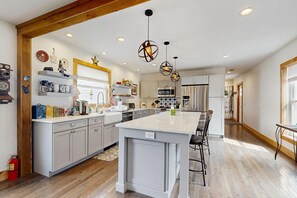 A modern kitchen with a central island, stainless steel appliances, and pendant lighting. - Family-Friendly Vermont Retreat Near Mount Snow | VAST Trail Access & Walk to Downtown (Wilmington)