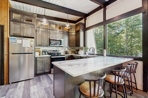 A modern kitchen with stainless steel appliances, a large island, and bar stools. - Mountain-view Wilmington home with well-appointed kitchen near Mount Snow (Wilmington)