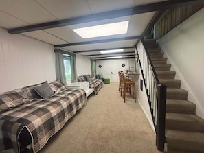 Une pièce comprenant un lit, un canapé, une table à manger avec des chaises et un escalier.