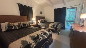 Une chambre avec deux lits, chacun doté d’une tête de lit et d’une couvre-lit sur le thème de la forêt. Il y a une table de chevet avec une lampe entre les deux lits, ainsi qu’une fenêtre avec des rideaux.