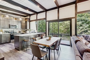 A modern kitchen with a large island, dining area with chairs, and a view of the outdoors. - Mountain-view Wilmington home with well-appointed kitchen near Mount Snow (Wilmington)