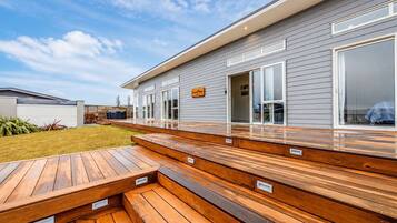A modern house with a wooden deck, a large sliding glass door, and a sign that reads 'Home.'