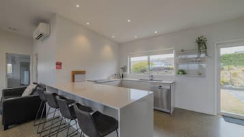 A modern kitchen with a central island, bar stools, a dishwasher, and a window with a view.