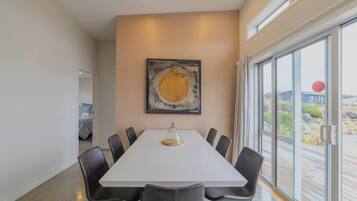 A conference room with a white table, black chairs, a large abstract painting, and a view of the outdoors through a glass door.