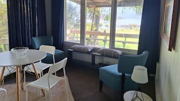 Una habitación acogedora con un banco, sillas, una mesa y vistas al exterior.