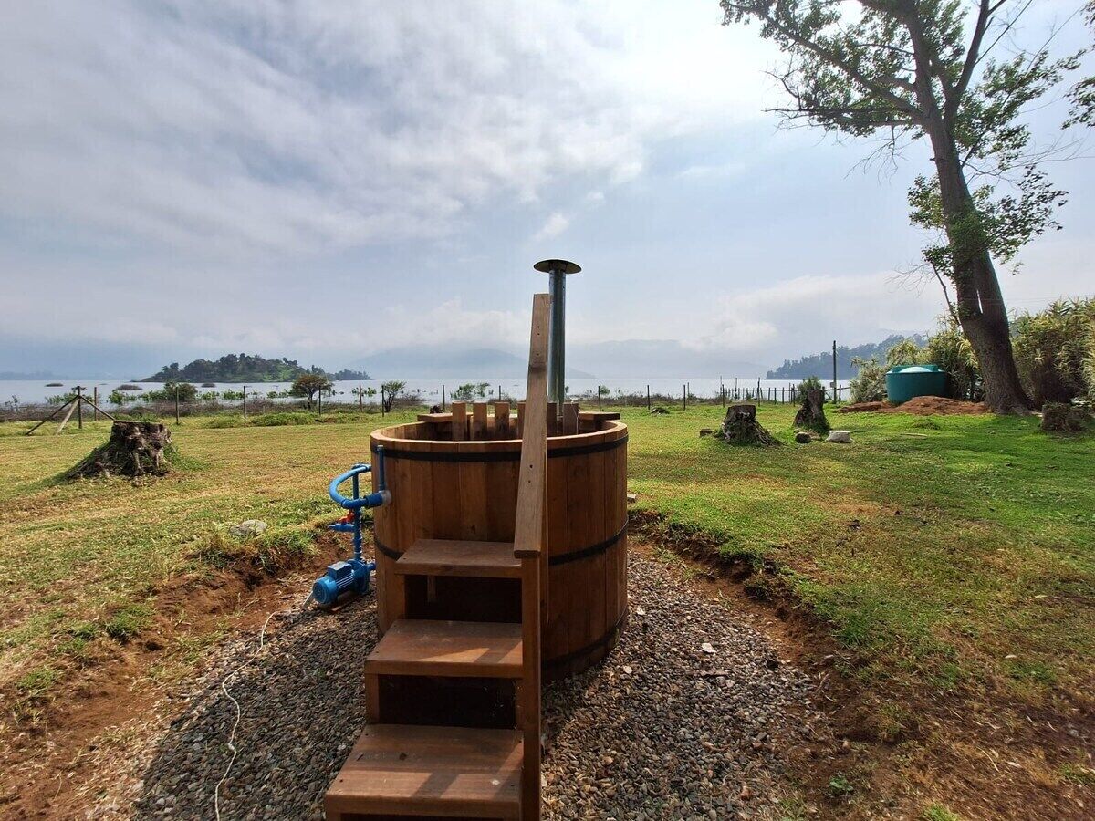 Estructura de sauna con chimenea, escalones y una bomba de agua azul.
