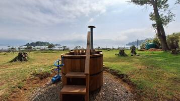 Estructura de sauna con chimenea, escalones y una bomba de agua azul.