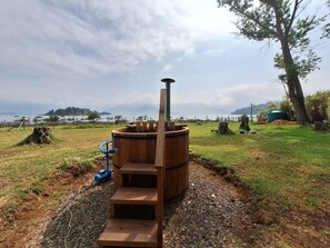 A sauna structure with a chimney, steps, and a blue water pump.