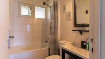 A bathroom with a bathtub, toilet, sink, and a mirror.