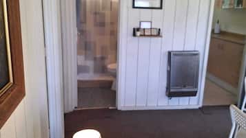 Una habitación con piso de madera, una lámpara, una silla, un televisor y un cuadro en la pared.