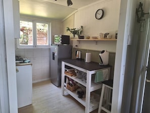 A compact kitchen with a refrigerator, a sink, a stove, and a small window.