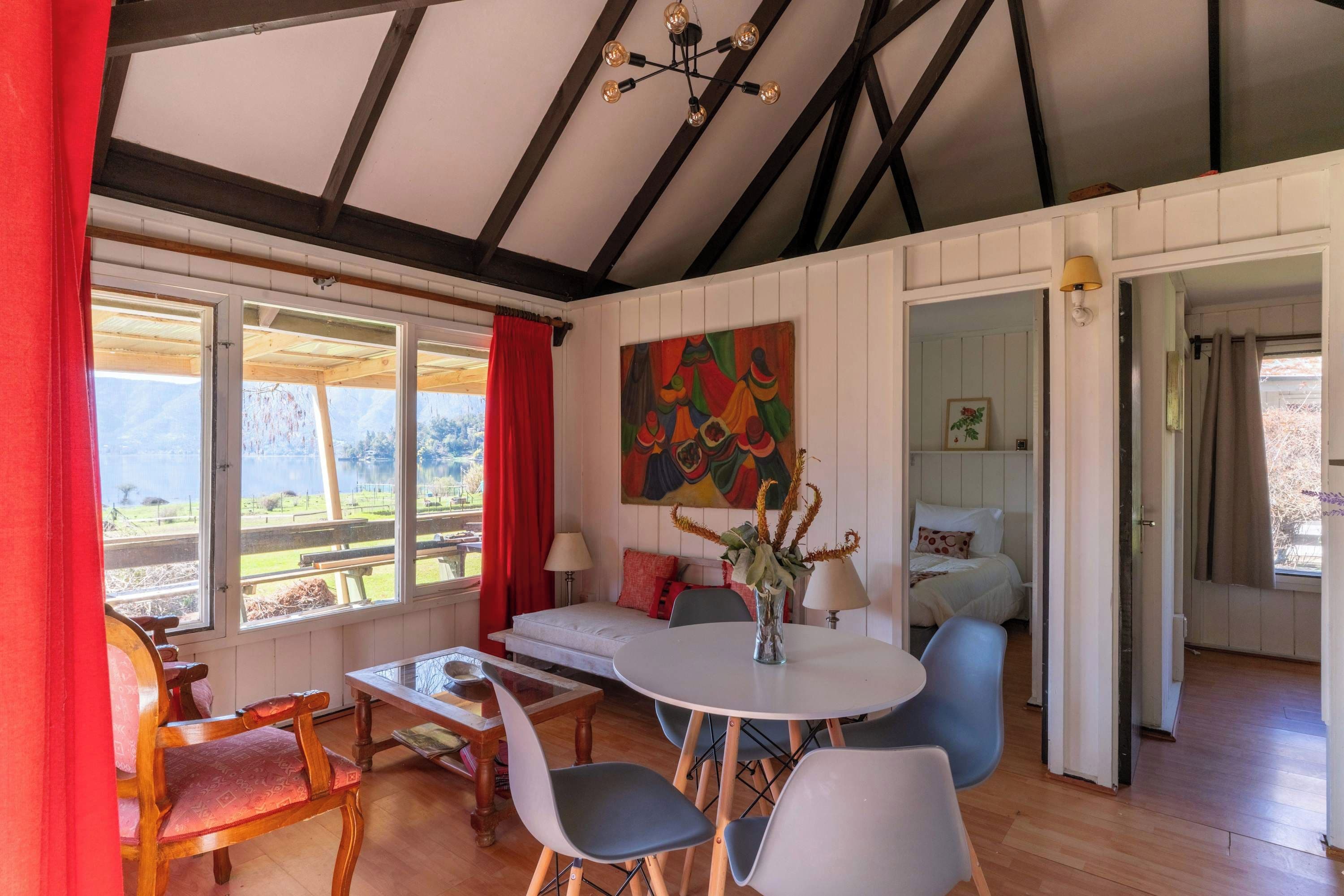 Une pièce comprenant une table à manger, des chaises, un canapé, un tableau et un lit.