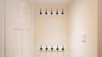 A hallway with two rows of black wall-mounted hooks on white walls.
