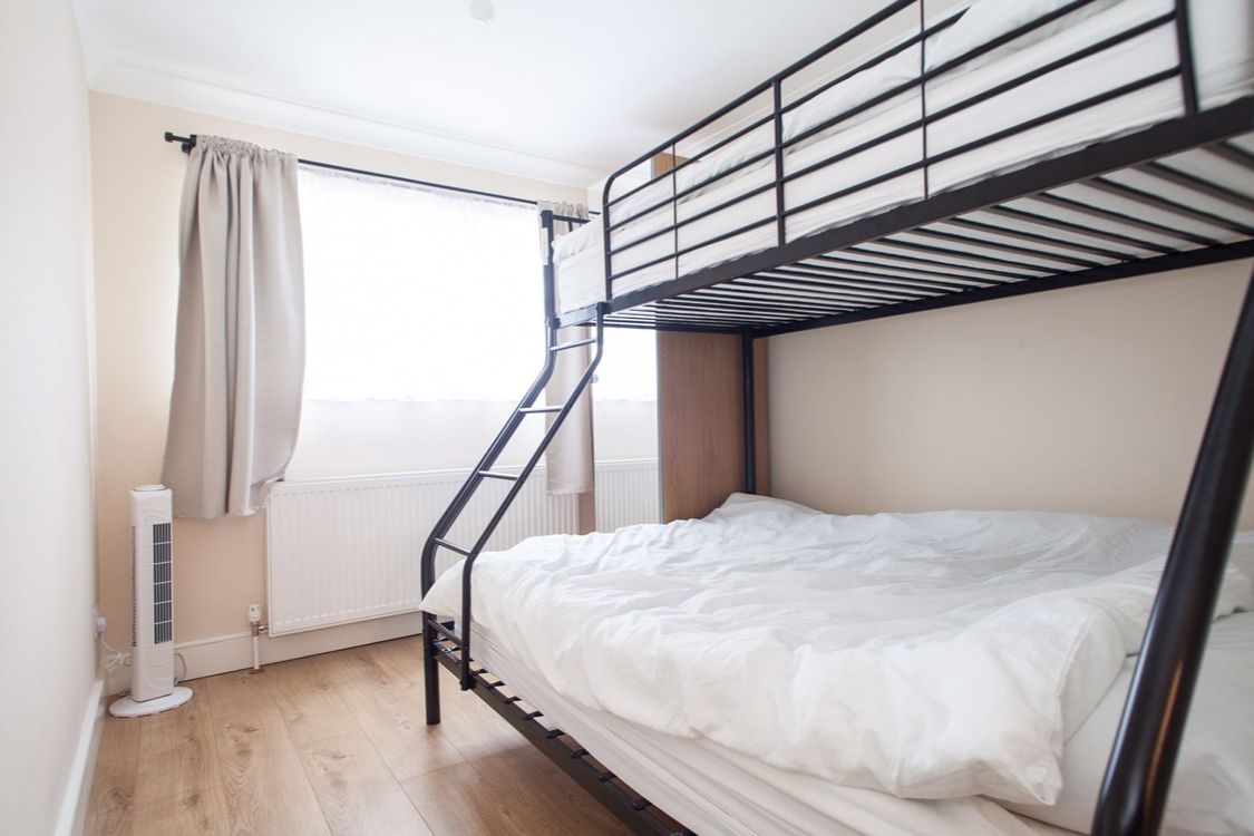 A bunk bed room with a window, a radiator, and a standing heater.