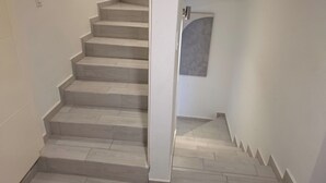 Una escalera con acabado de madera claro que conduce a un rellano con un aplique de pared.