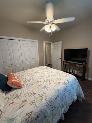 Ein Schlafzimmer mit einem Bett, einem Deckenventilator, einem Fernseher und einem Kleiderschrank.
