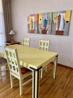 A dining area with a table and chairs, a lamp, and a painting on the wall. - Lindo departamento en la mejor zona de Polanco (Cdmx)