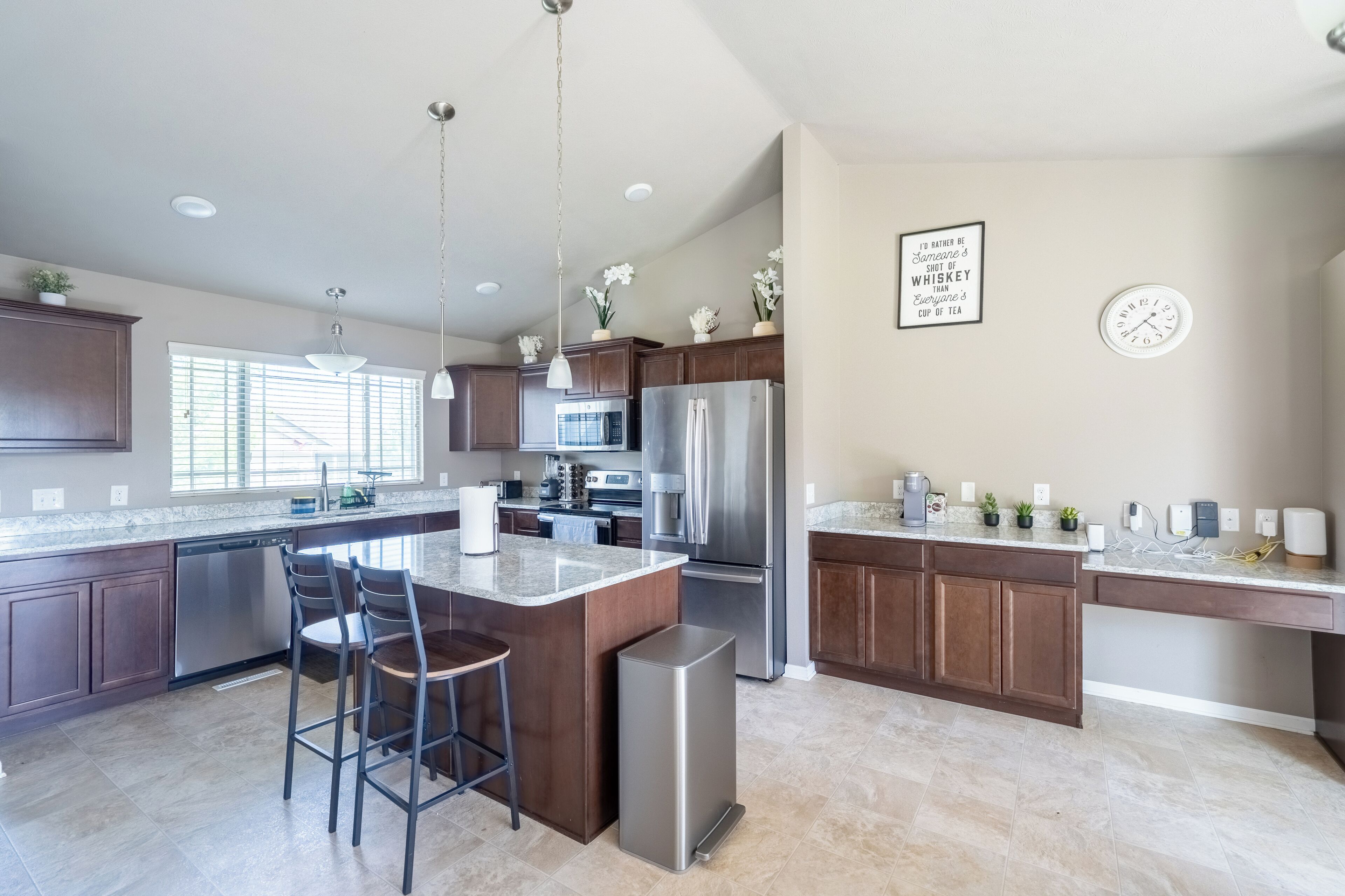 A modern kitchen with a central island, stainless steel appliances, and a dining area with bar stools.